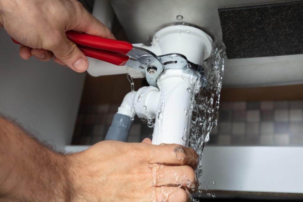 Male Plumber Fixing White Sink Pipe